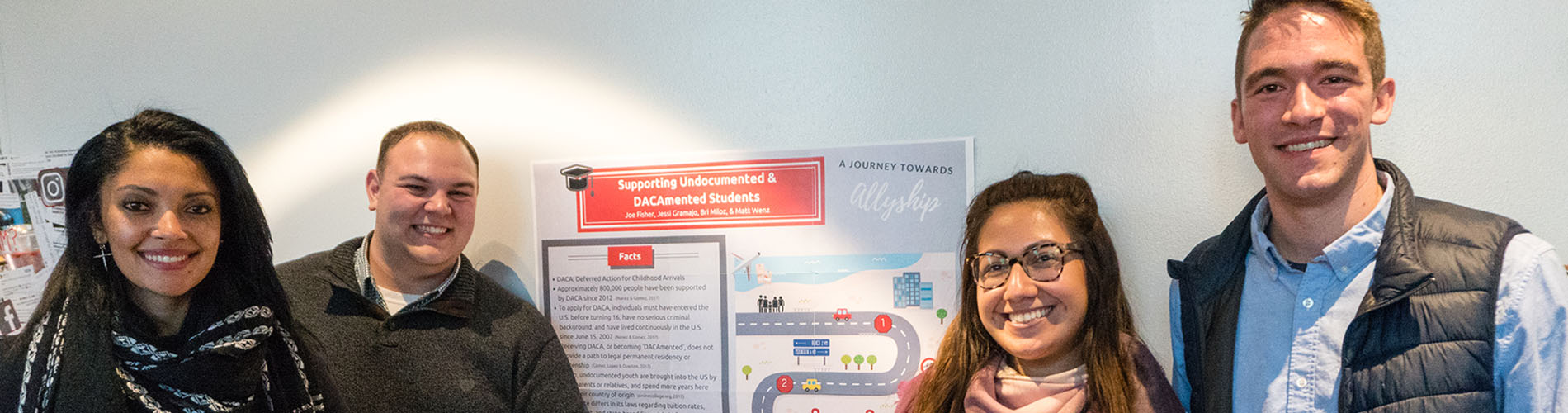 Four master's students stand in front of a project poster and smile at the camera.